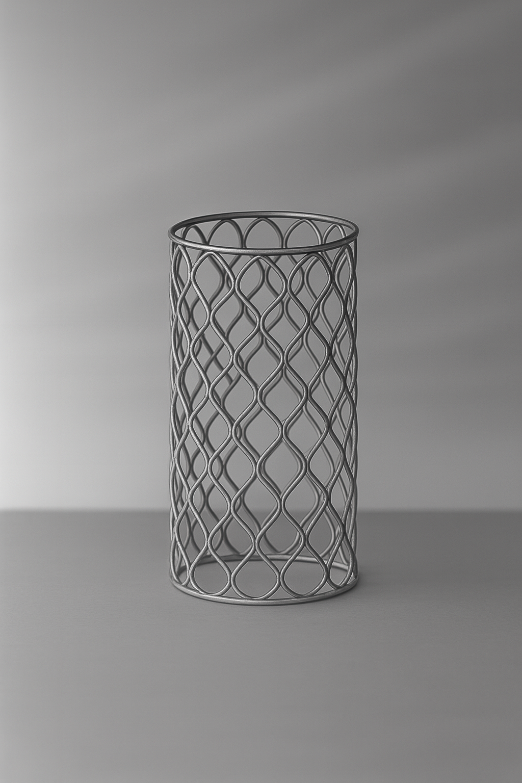 Im Vordergrund sieht man ein aus Draht gestrickten Zylinder. Der Hintergrund ist gräulich verwaschen.